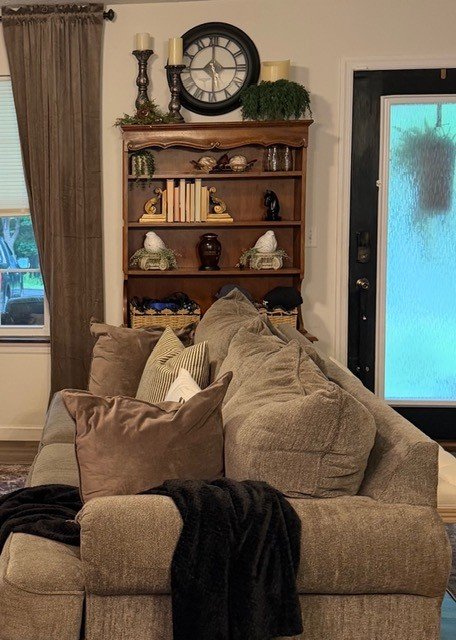 Room view with sofa vintage wood hutch styled near the front door behind a sofa in French country living room. 
