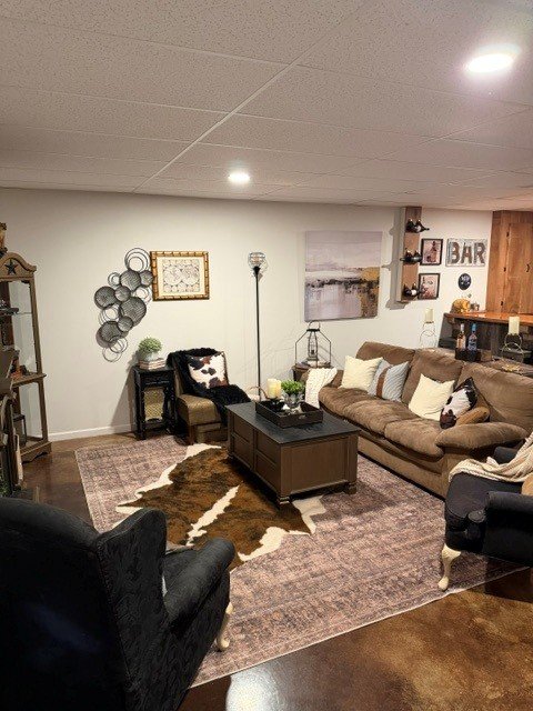 Basement rec room with white walls, blackened bronze accent wall, and warm lighting.