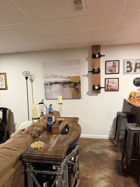 Basement rec room with white walls, blackened bronze accent wall, and warm lighting.