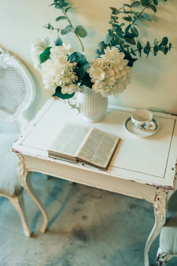 Distressed white table with flowers in a  Shabby Chic room